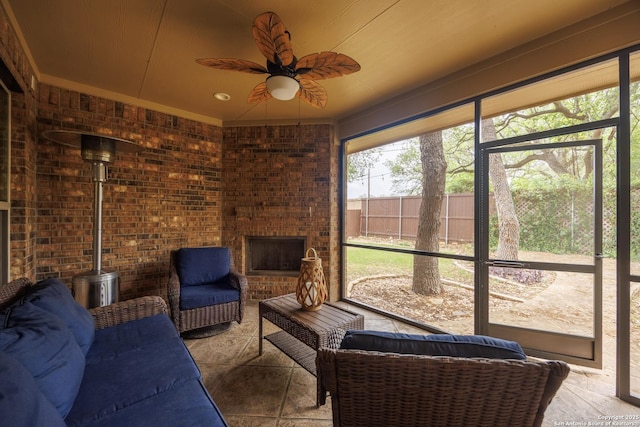 sunroom featuring ceiling fan and a fireplace