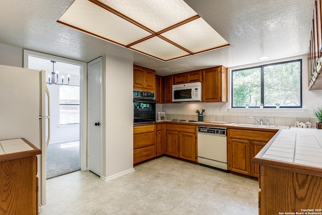 19750 Encino Way, San Antonio, TX 78259 - kitchen with white appliances, tile counters, a sink, brown cabinets, and a textured ceiling