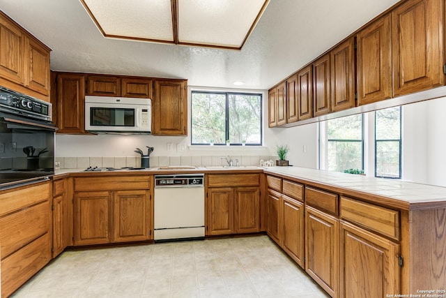 19750 Encino Way, San Antonio, TX 78259 - kitchen featuring white appliances, brown cabinets, tile counters, a textured ceiling, and a sink