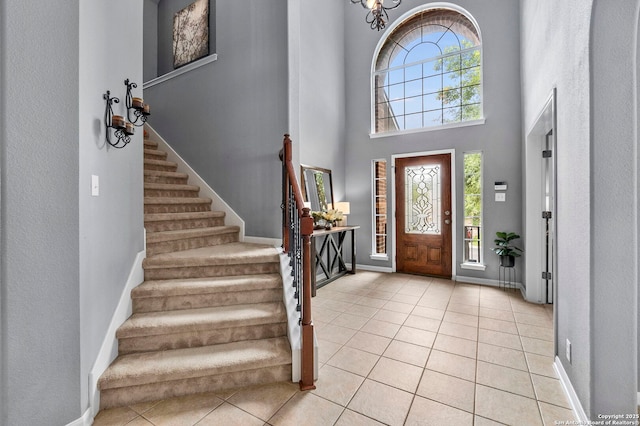 foyer featuring baseboards, a high ceiling, light tile patterned floors, and stairway