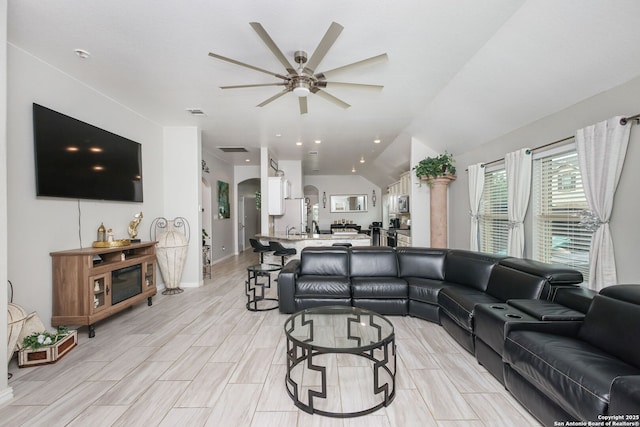 living room featuring a ceiling fan, arched walkways, lofted ceiling, and wood finish floors
