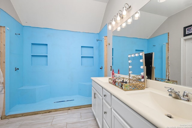 bathroom featuring a sink, walk in shower, double vanity, and lofted ceiling