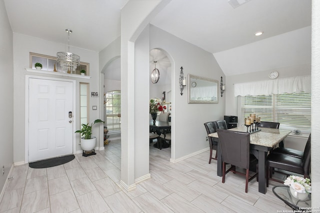 entrance foyer featuring arched walkways, baseboards, vaulted ceiling, and a wealth of natural light