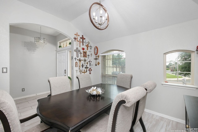 dining space with arched walkways, baseboards, a chandelier, and lofted ceiling