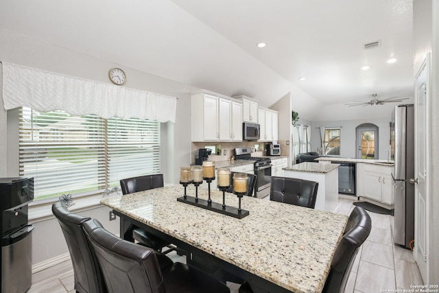 kitchen featuring visible vents, a kitchen breakfast bar, a center island, white cabinetry, and appliances with stainless steel finishes