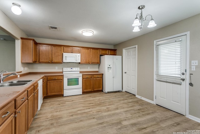 5735 Cardinal Fls, San Antonio, TX 78239 - kitchen with brown cabinets, a sink, a chandelier, light wood-style floors, and white appliances