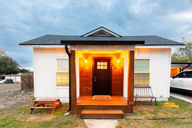 property entrance with roof with shingles and fence