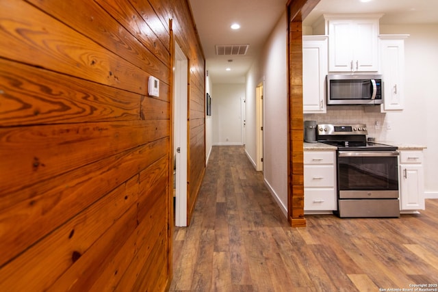 hall featuring dark wood-style flooring, baseboards, visible vents, and recessed lighting