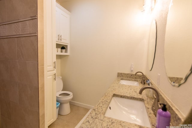 full bathroom with double vanity, toilet, a sink, and tile patterned flooring