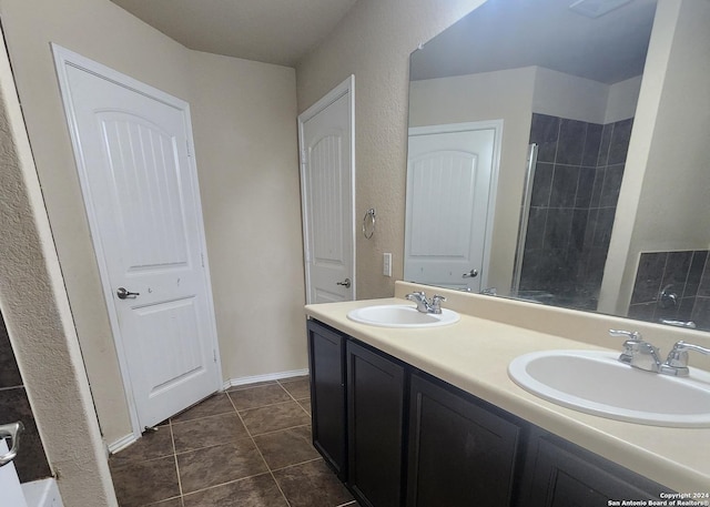full bath featuring double vanity, a sink, tile patterned floors, and tiled shower