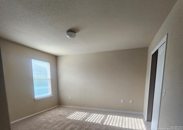 carpeted spare room with baseboards and a textured ceiling