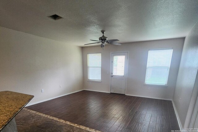 unfurnished living room featuring ceiling fan, dark wood-style flooring, a textured ceiling, and visible vents