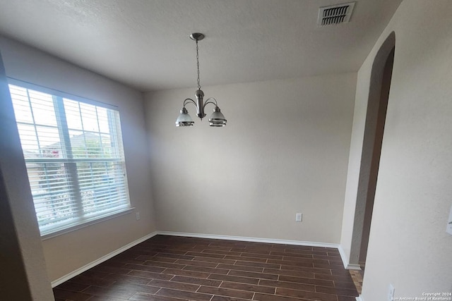 unfurnished room featuring plenty of natural light, baseboards, visible vents, and an inviting chandelier