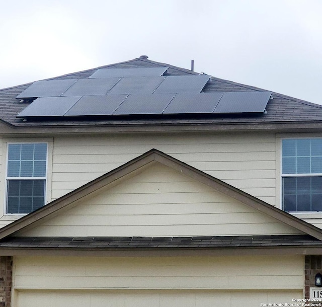 view of property exterior featuring solar panels and roof with shingles