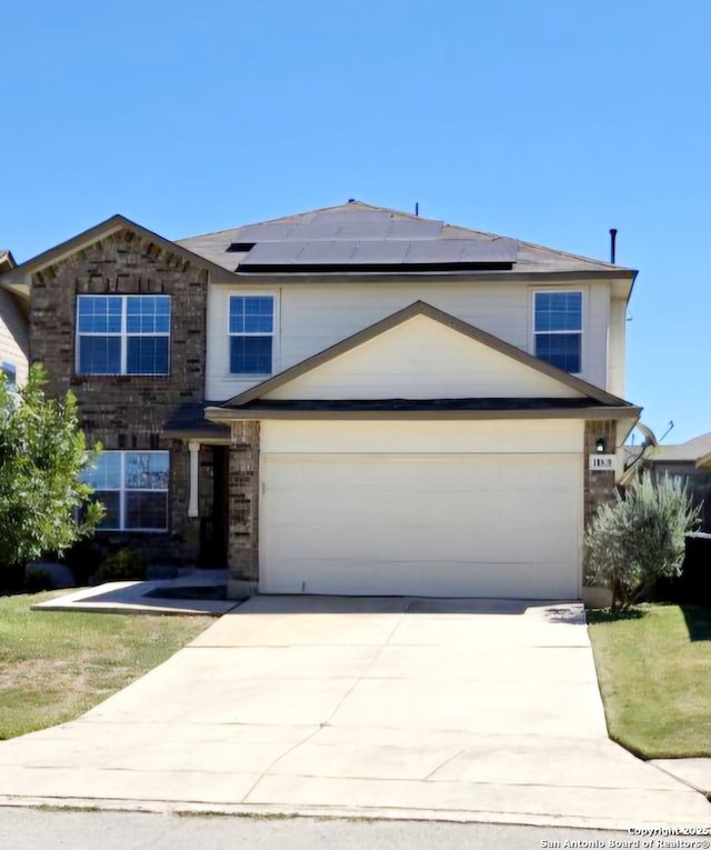 traditional-style home featuring an attached garage, concrete driveway, solar panels, and brick siding