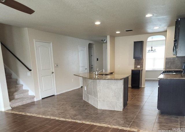 kitchen featuring visible vents, a kitchen island with sink, recessed lighting, arched walkways, and a sink