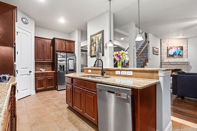kitchen with pendant lighting, appliances with stainless steel finishes, a sink, light tile patterned floors, and open floor plan
