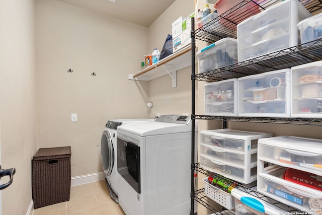 washroom featuring light tile patterned floors, baseboards, laundry area, and independent washer and dryer