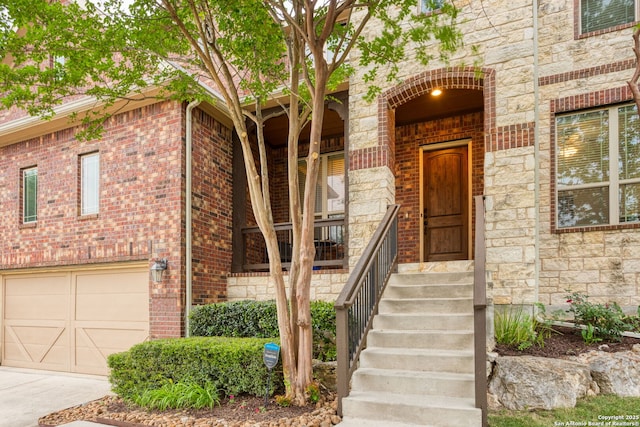 doorway to property featuring covered porch, an attached garage, brick siding, and stone siding