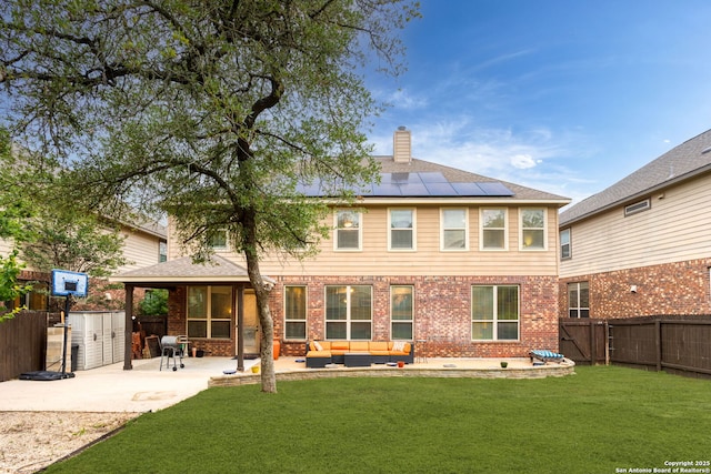 rear view of house featuring solar panels, a fenced backyard, a yard, a patio, and outdoor lounge area