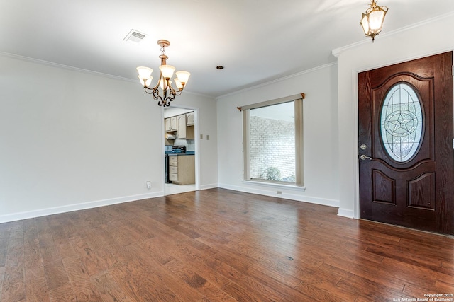 entrance foyer featuring a chandelier, healthy amount of natural light, ornamental molding, and dark wood finished floors