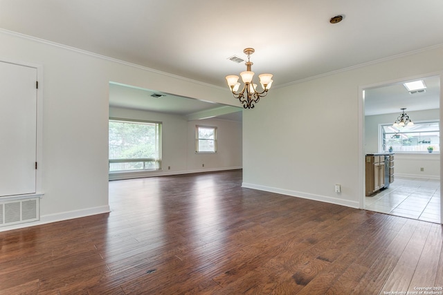 unfurnished room with a chandelier, hardwood / wood-style floors, ornamental molding, and baseboards