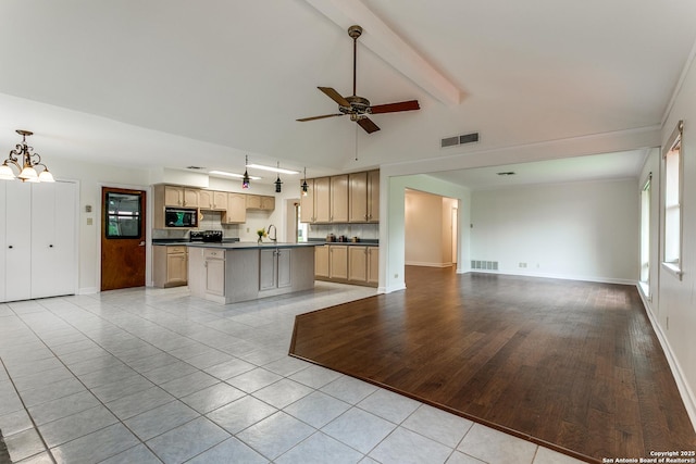 kitchen with open floor plan, dark countertops, black microwave, light tile patterned floors, and ceiling fan