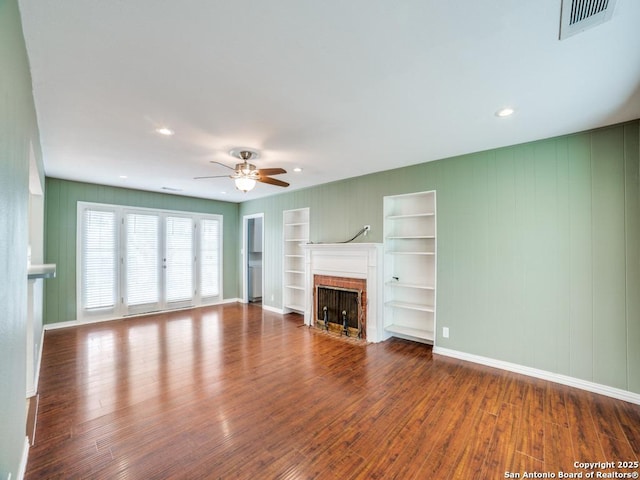 9327 Fernglen Dr, San Antonio, TX 78240 - unfurnished living room with ceiling fan, visible vents, a fireplace with flush hearth, built in shelves, and wood finished floors
