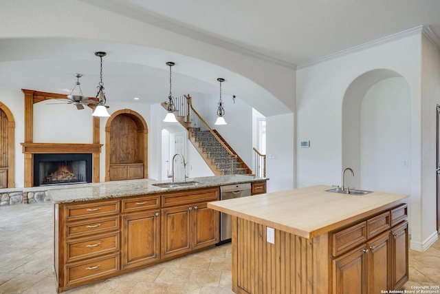 kitchen with stainless steel dishwasher, a sink, a ceiling fan, and a kitchen island with sink