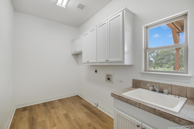 clothes washing area with cabinet space, washer hookup, a sink, hookup for a gas dryer, and hookup for an electric dryer