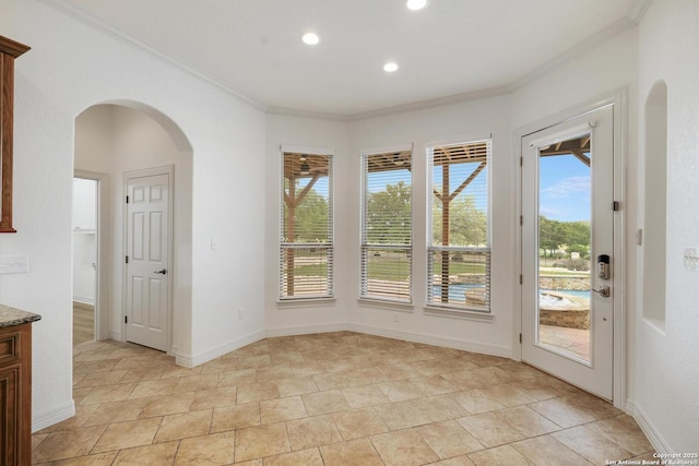 unfurnished dining area featuring plenty of natural light, arched walkways, ornamental molding, and recessed lighting