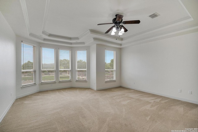 unfurnished room with visible vents, a tray ceiling, light carpet, and a healthy amount of sunlight