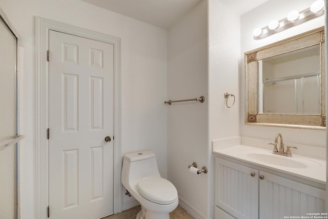 bathroom with vanity, a shower with door, baseboards, and toilet