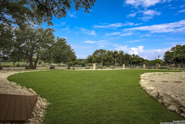 view of property's community with a lawn and fence