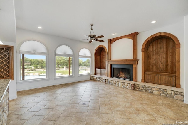 unfurnished living room featuring recessed lighting, a ceiling fan, stone finish flooring, and a fireplace