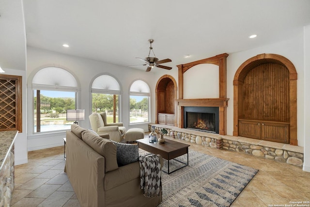 living room with a large fireplace, recessed lighting, and stone tile floors