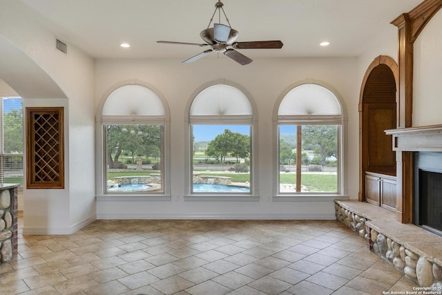 unfurnished living room featuring a fireplace with raised hearth, visible vents, and plenty of natural light