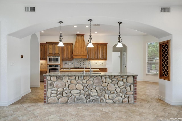 kitchen with visible vents, appliances with stainless steel finishes, arched walkways, a sink, and baseboards