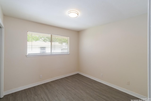 unfurnished room with baseboards and dark wood-style flooring