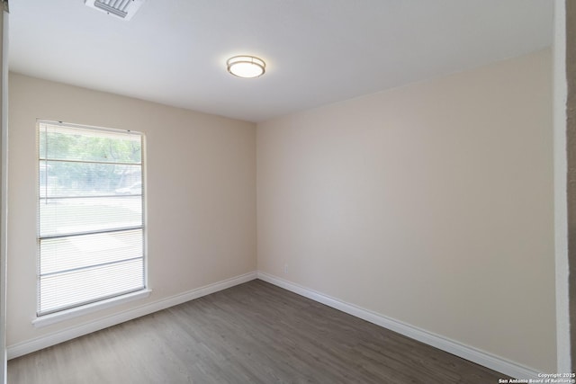 spare room featuring baseboards, visible vents, and dark wood-type flooring