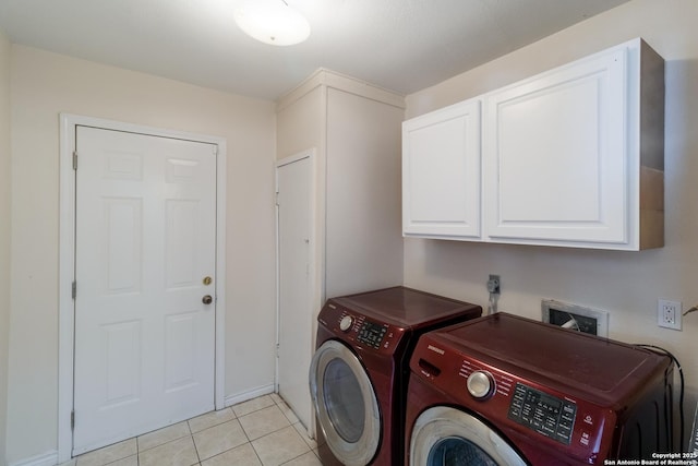 washroom featuring cabinet space, washing machine and dryer, and light tile patterned floors