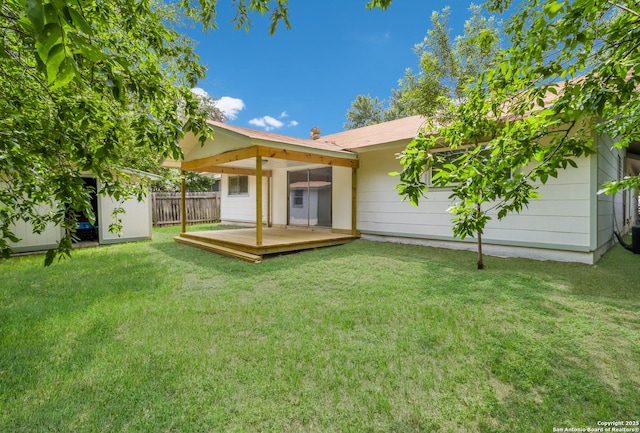 rear view of property featuring fence, a deck, a yard, an outbuilding, and a storage shed
