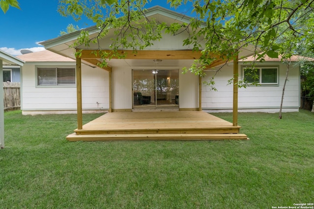 back of house featuring a lawn, a wooden deck, and fence