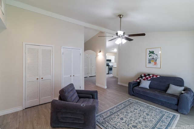 living room with arched walkways, baseboards, a ceiling fan, and wood finished floors