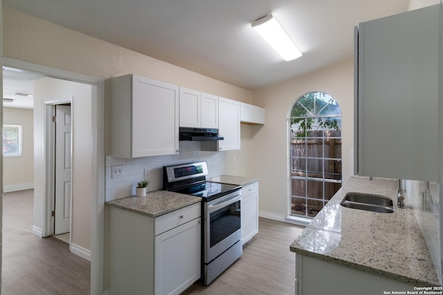kitchen featuring stainless steel electric stove, tasteful backsplash, under cabinet range hood, and light wood-type flooring