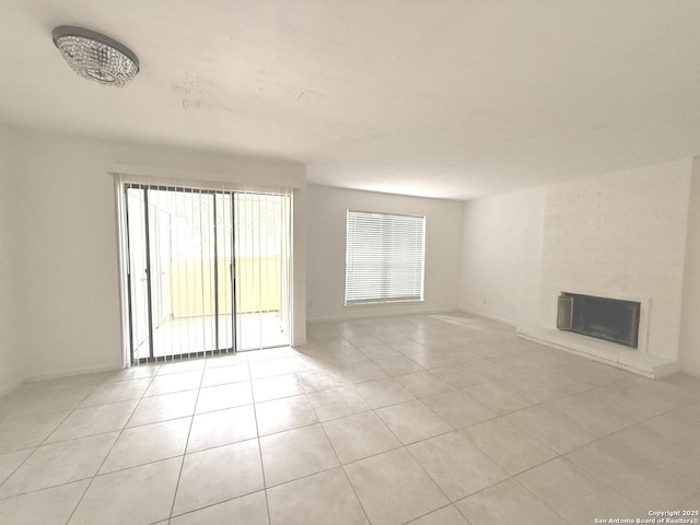 unfurnished living room with baseboards, light tile patterned floors, and a fireplace