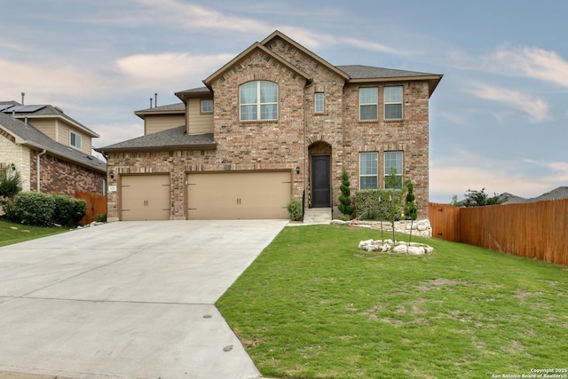 traditional-style home featuring a garage, fence, a front yard, brick siding, and driveway