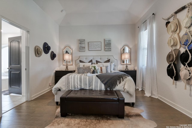 bedroom with baseboards, wood finished floors, and connected bathroom