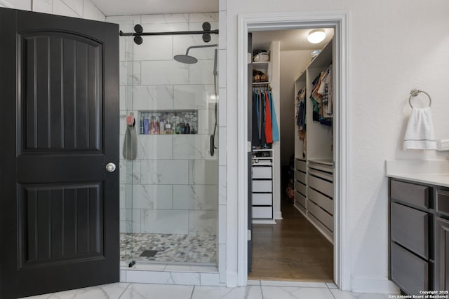 full bath with vanity, a walk in closet, a stall shower, and marble finish floor