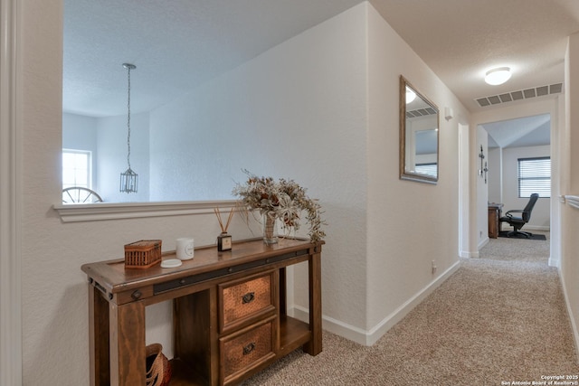 hallway featuring baseboards, carpet flooring, and visible vents